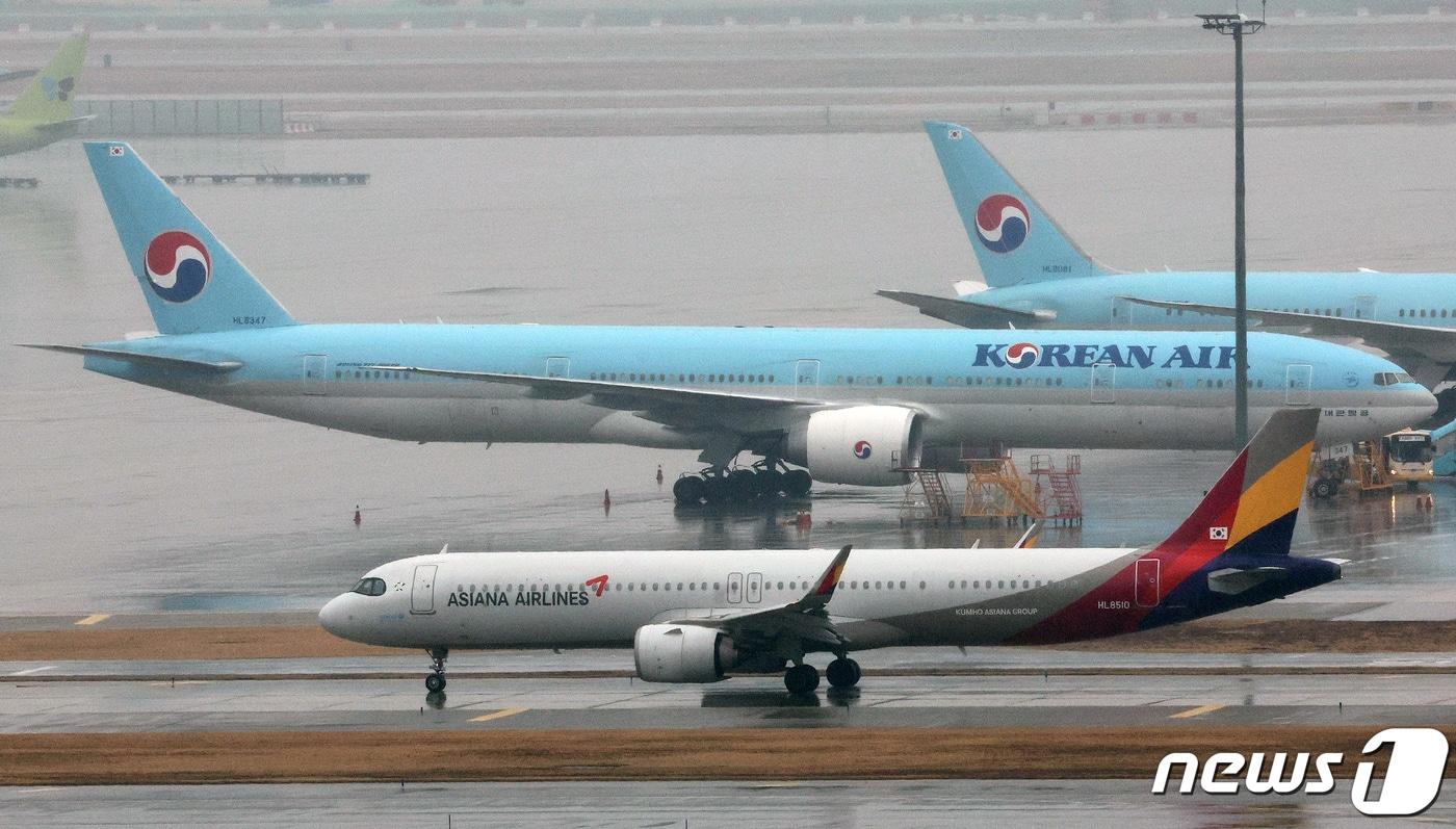 본문 이미지 - 14일 오후 인천국제공항 계류장에 세워진 대한항공 항공기 앞으로 아시아나 항공기가 지나가고 있다. 2024.1.14/뉴스1 ⓒ News1 장수영 기자