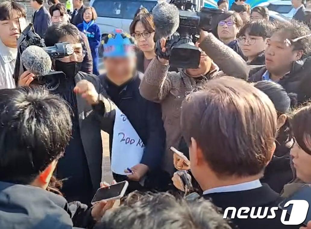 본문 이미지 - 이재명 더불어민주당 대표가 2일 오전 부산 가덕도에서 신원미상인에게 피습을 당했다. 사진은 파란색 종이 왕관을 쓴 신원미상(60대 남자)의 용의자가 범행을 위해 이 대표에게 다가서는 모습. (유튜브 정양일 TV 캡쳐) 2024.1.2/뉴스1