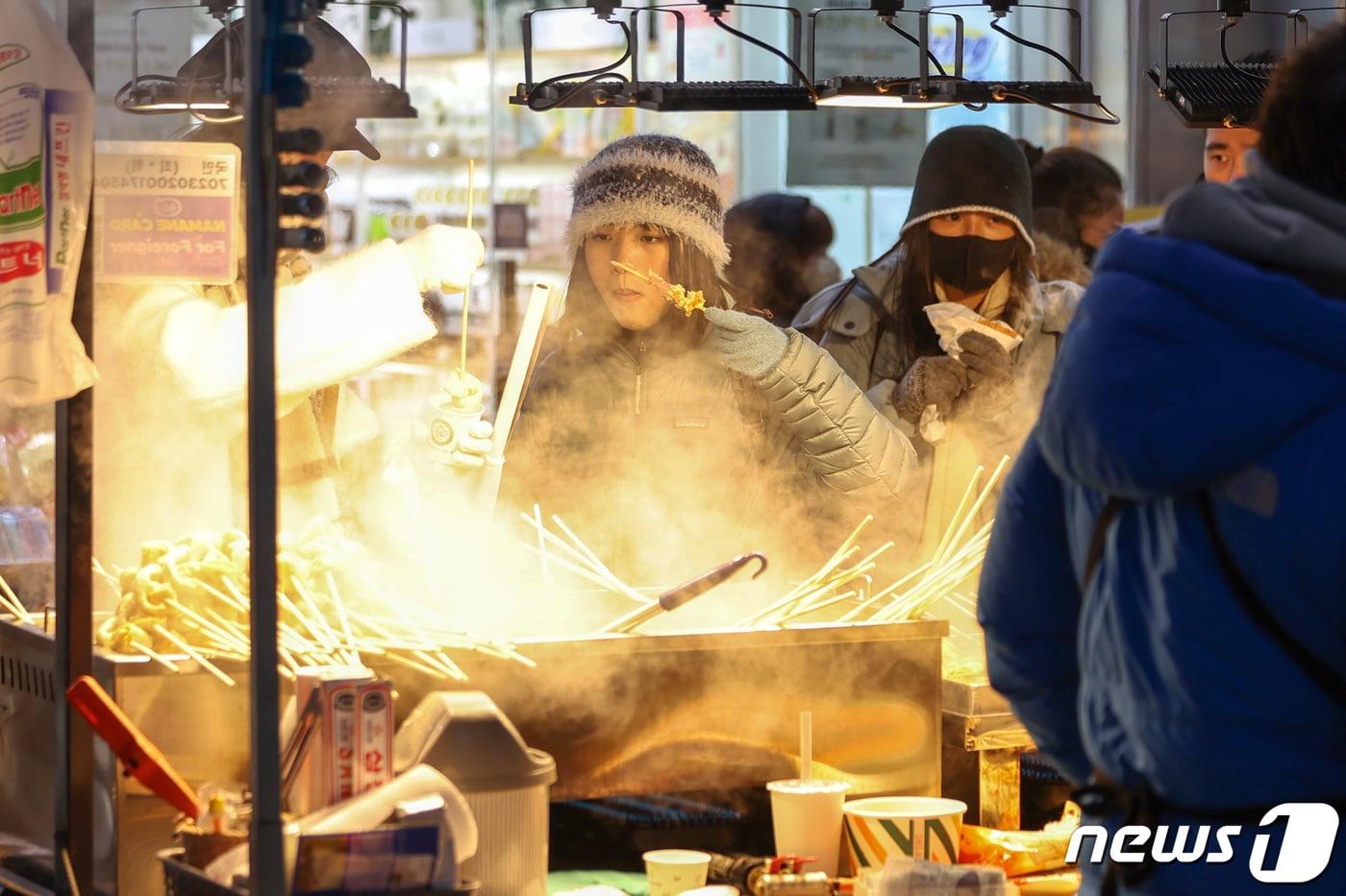 본문 이미지 - 전국에 한파가 몰아닥친 지 23일 저녁 서울 중구 명동거리의 포장마차에서 외국인 관광객들이 뜨거운 김이 피어오르는 어묵을 맛보고 있다. 2024.1.23/뉴스1 ⓒ News1 민경석 기자