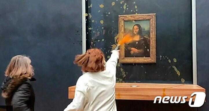 본문 이미지 - 여성 환경운동가 2명이 28일(현지시간) 루브르 박물관에 전시된 모나리자 작품에 수프를 투척하고 있다. - BBC 동영상 갈무리