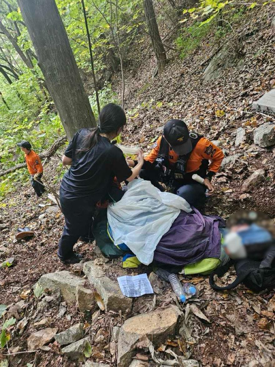 본문 이미지 - 임산물 채취 하러 왔다가 넘어져 다친 60대 여성 치료하는 인제소방서 구조대원들.(인제소방서 제공)