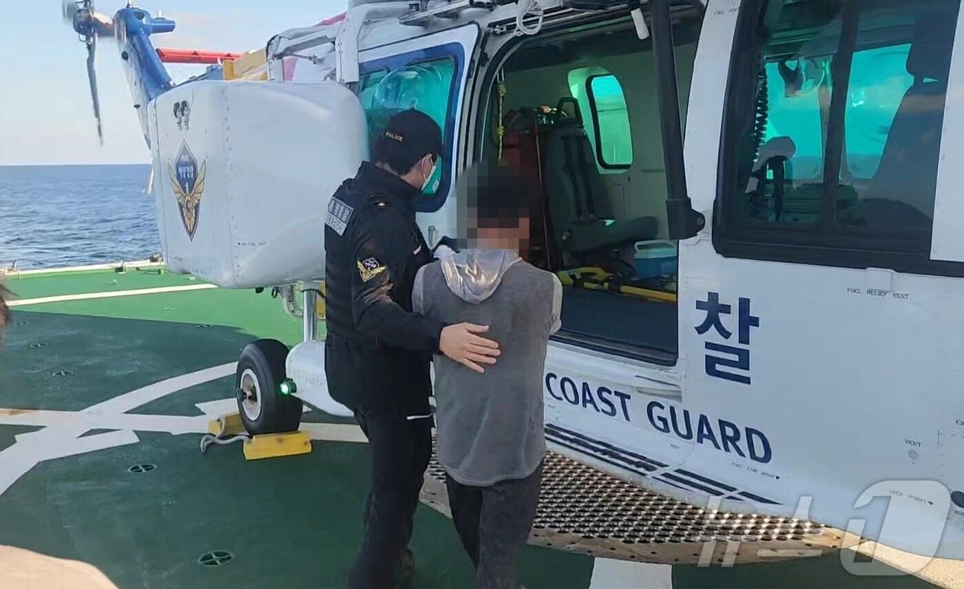 본문 이미지 - 13일 러시아해역서 조업하다 손가락이 절되는 사고를 입은 외국인 선원을 헬기로 이송하는 동해해경청 소속 경찰관.(동해해경청 제공) 2024.10.13/뉴스1