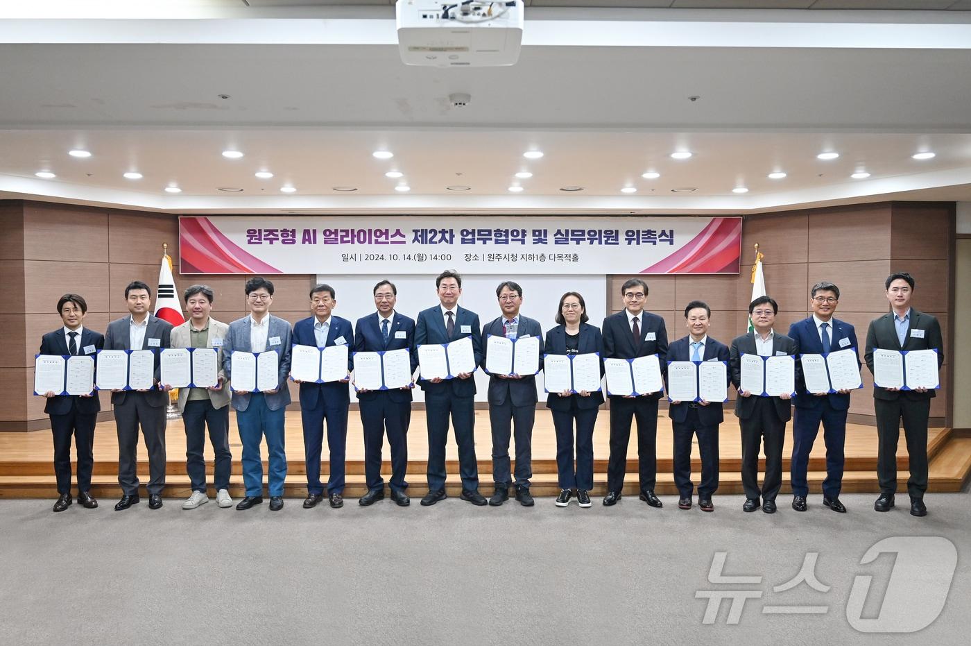 강원 원주시의 ‘원주형 AI 얼라이언스 구축 및 산업생태계 조성을 위한 업무협약’ 체결식과 실무위원 위촉식이 14일 오후 시청 다목적홀에서 진행된 가운데 이날 원강수 원주시장과 협약 당사자인 AI 분야 13개 기업‧기관‧단체‧대학 관계자들이 기념 사진을 촬영하고 있다. (원주시 제공) 2024.10.14/뉴스1