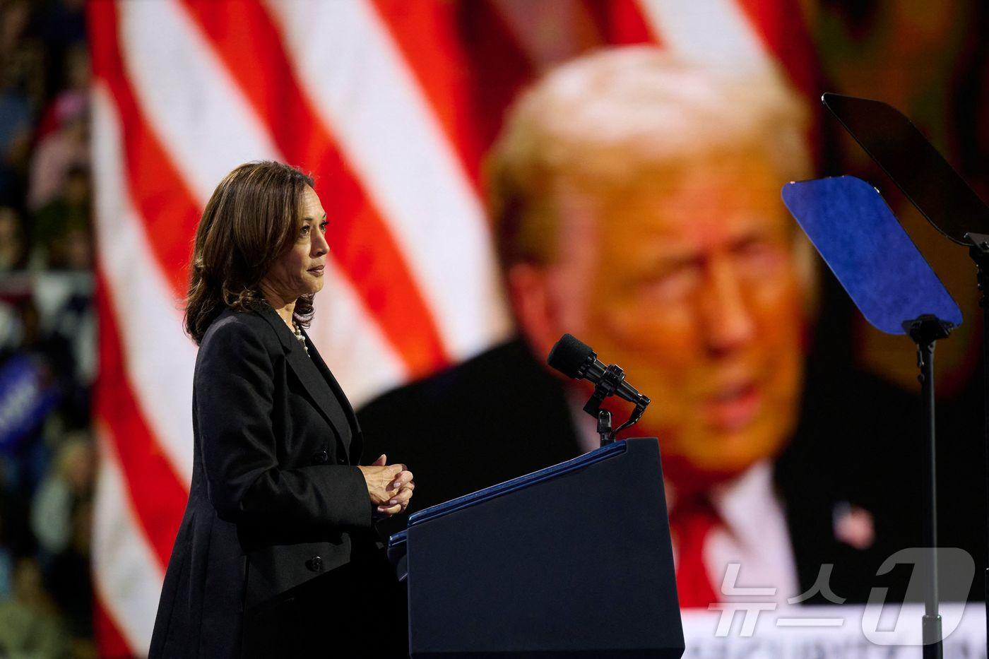 본문 이미지 - 미국 민주당 대통령 후보인 카멀라 해리스 부통령이 14일 (현지시간) 펜실베이니아주 이리에서 도널드 트럼프 전 대통령의 영상을 배경으로 유세를 하고 있다. 2024.10.15 ⓒ AFP=뉴스1 ⓒ News1 우동명 기자