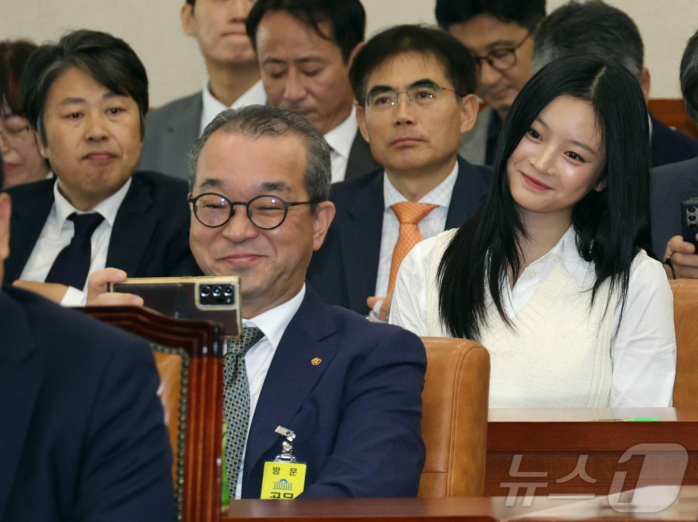 본문 이미지 - 정인섭 한화오션 거제사업장 사장이 15일 서울 여의도 국회 환경노동위원회에서 열린 경제사회노동위원회, 중앙노동위원회, 최저임금위원회 등에 대한 국정감사에서 그룹 뉴진스(NewJeans)의 하니와 셀프 카메라를 찍고 있다. 2024.10.15/뉴스1 ⓒ News1 국회사진취재단