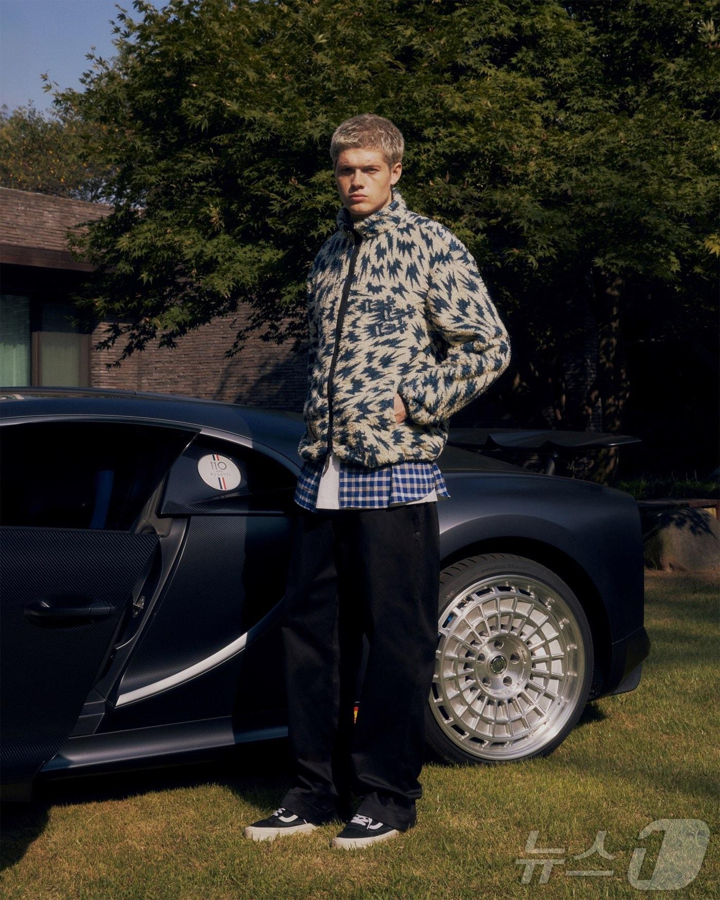 본문 이미지 - 한국타이어의 모터 컬쳐 브랜드 '드라이브(DRIVE)'와 모터 컬쳐 패션 브랜드 '슈퍼패스트(superfast)'가 2024년도 F/W(가을·겨울) 시즌 2차 컬렉션으로 출시한 플리스 재킷을 모델이 입고 있는 모습. 모델 옆은 한국타이어가 고성능 타이어 개발을 위해 보유·운용 중인 하이퍼카 '부가티 시론 스포츠 110 ANS'(한국타이어앤테크놀로지 제공). 2024.10.17.