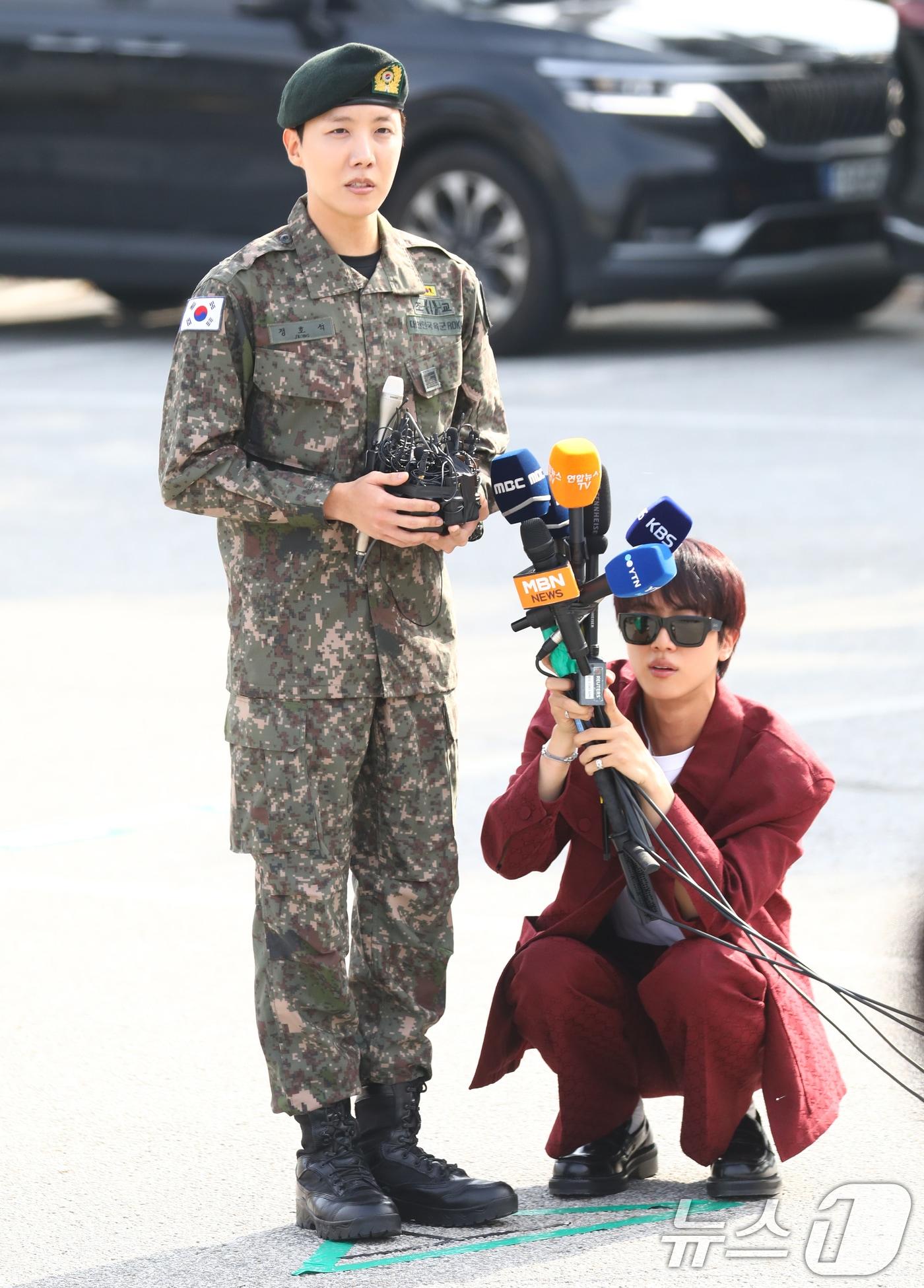 본문 이미지 - 방탄소년단(BTS) 진(오른쪽)이 17일 강원도 원주시에 위치한 육군 제36보병사단 백호 신병교육대에서 전역 인사를 하는 제이홉의 인터뷰를 위해 마이크 도우미를 자처하고 있다. 2024.10.17./뉴스1 ⓒ News1 권현진 기자