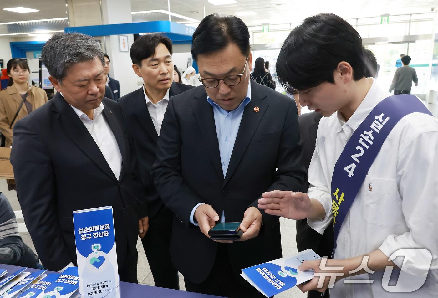 김병환 금융위원장이 지난 10월25일 오전 서울 여의도 성모병원 내 실손보험 청구 전산화 홍보 부스를 찾아 현장 안내직원의 설명을 듣고 있다. (금융위원회 제공) 2024.10.25/뉴스1