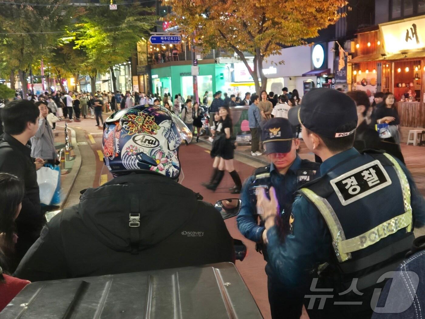 본문 이미지 - 핼러윈 데이를 앞둔 주말인 26일 오후 서울경찰청 기동순찰대 소속 경찰관들이 순찰 도중 '차 없는 거리'로 진입한 오토바이를 붙잡아 범칙금을 부과하고 있다.ⓒ 뉴스1 남해인 기자 