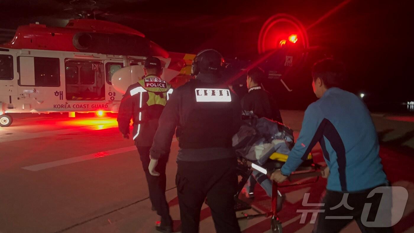 본문 이미지 - 울릉도에서 두개골이 골절된 응급환자를 헬기로 옮기는 해양경찰관.(동해해경청 제공) 2024.10.28/뉴스1