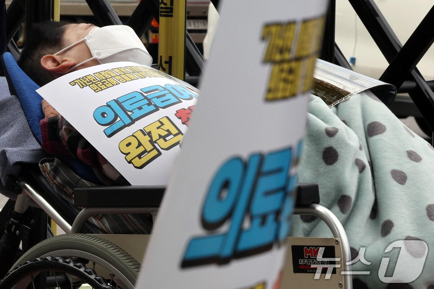 지난해 10월 29일 오후 서울 종로구 정부서울청사 인근에서 참여연대와 빈곤사회연대 등 시민단체 주최로 열린 의료급여 정률제 개악 철회 촉구 결의대회에 한 집회 참석자가 휠체어에 누워 있다./뉴스1 ⓒ News1 이동해 기자