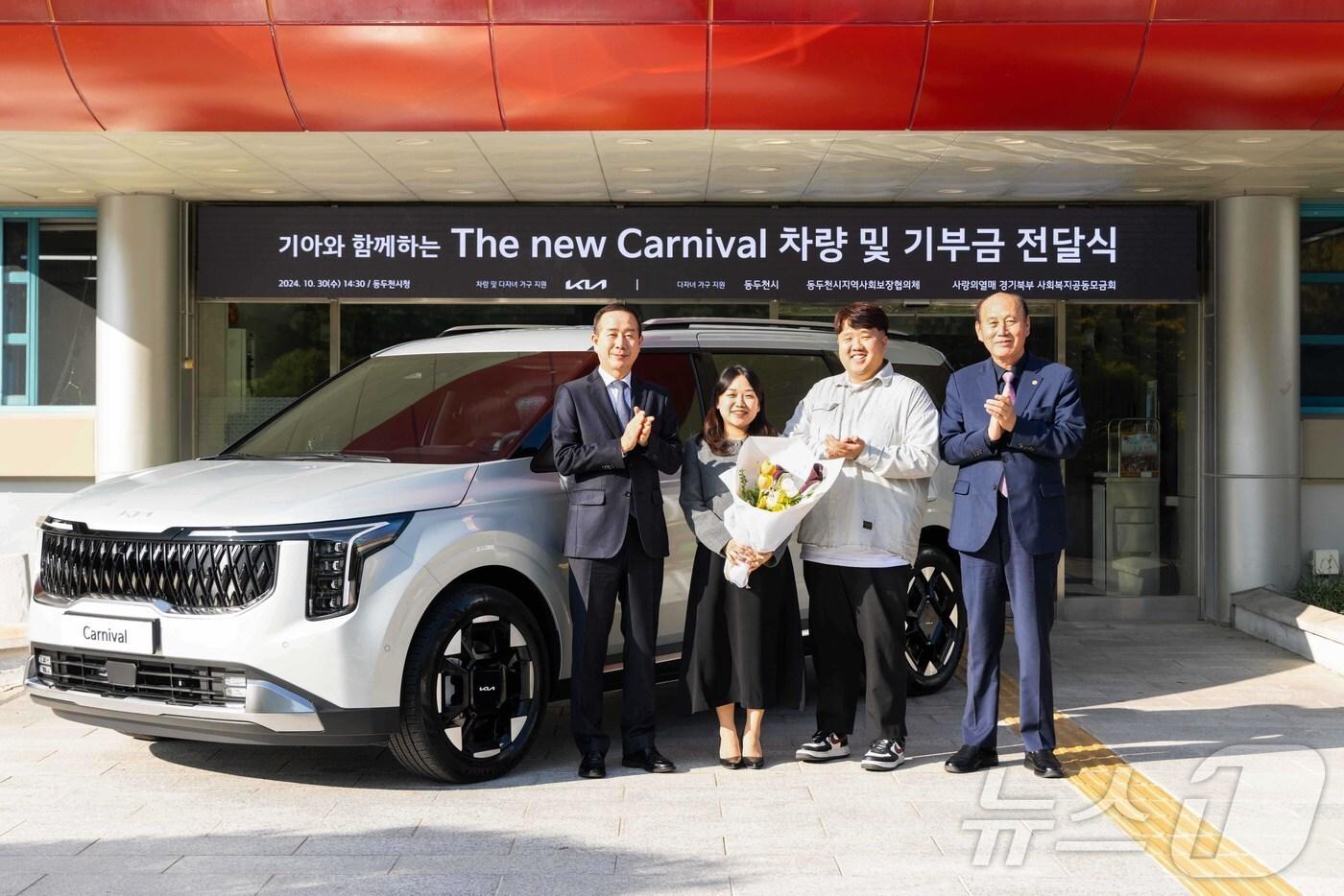 본문 이미지 - ‘The 2025 카니발’ 9인승 차량 전달식에서 기아 국내사업본부장 정원정 부사장, 사공혜란·김준영 부부, 박형덕 동두천시장이 기념 사진을 촬영하고 있다. 