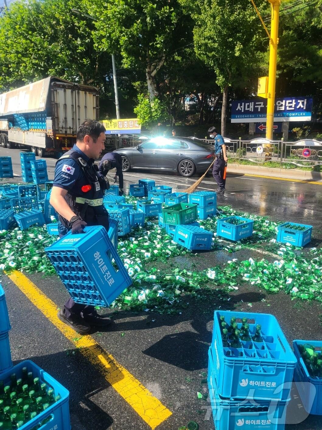 본문 이미지 - 지난 1일 오전 9시 30분쯤 대구 서구 중리네거리에 25톤 윙바디트럭 내에 있던 소주 박스(50여병)가 도로 위에 떨어져 경찰이 현장을 수습하고 있다. (대구경찰청 제공)/뉴스1