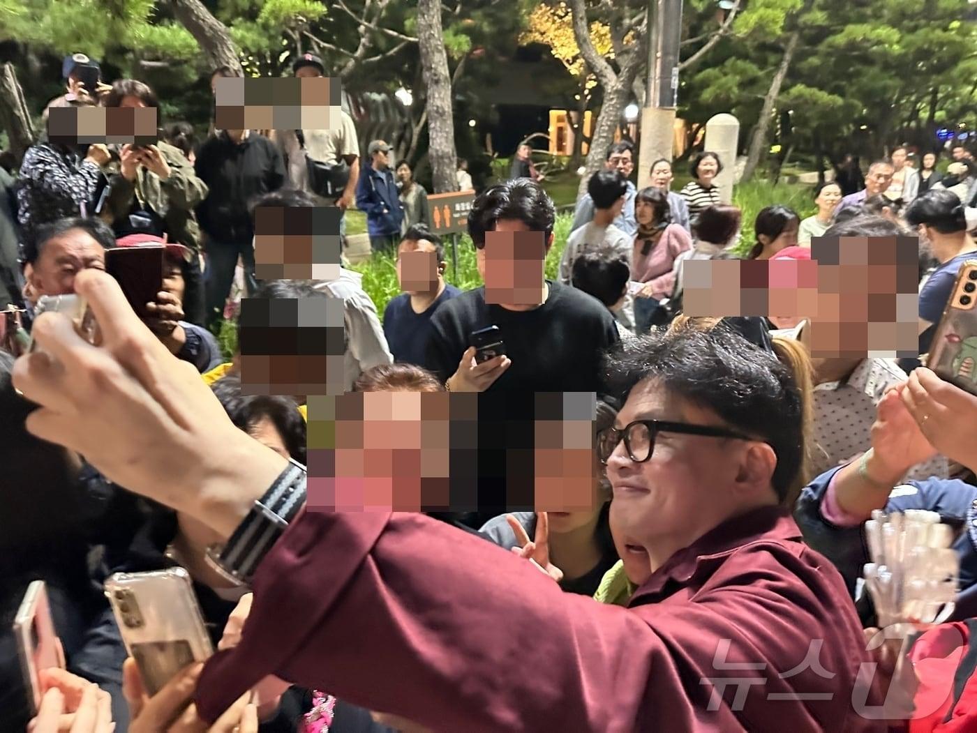 본문 이미지 - 한동훈 국민의힘 대표가 5일 밤 부산 해운대해수욕장에서 시민들과 사진 촬영을 하고 있다. (독자 사진 제공)