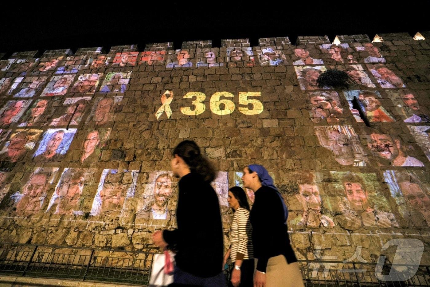 본문 이미지 - 팔레스타인 무장정파 하마스의 이스라엘 공격으로 촉발된 가자지구 전쟁이 1주년을 맞기 하루 전날인 6일(현지시간) 이스라엘 예루살렘 성벽에 희생자들을 기리는 사진이 그들을 기리는 노란 리본과 함께 떠 있다. 숫자 365는 1년을 의미하는 것이다. 2024.10.06. ⓒ AFP=뉴스1 ⓒ News1 조소영 기자