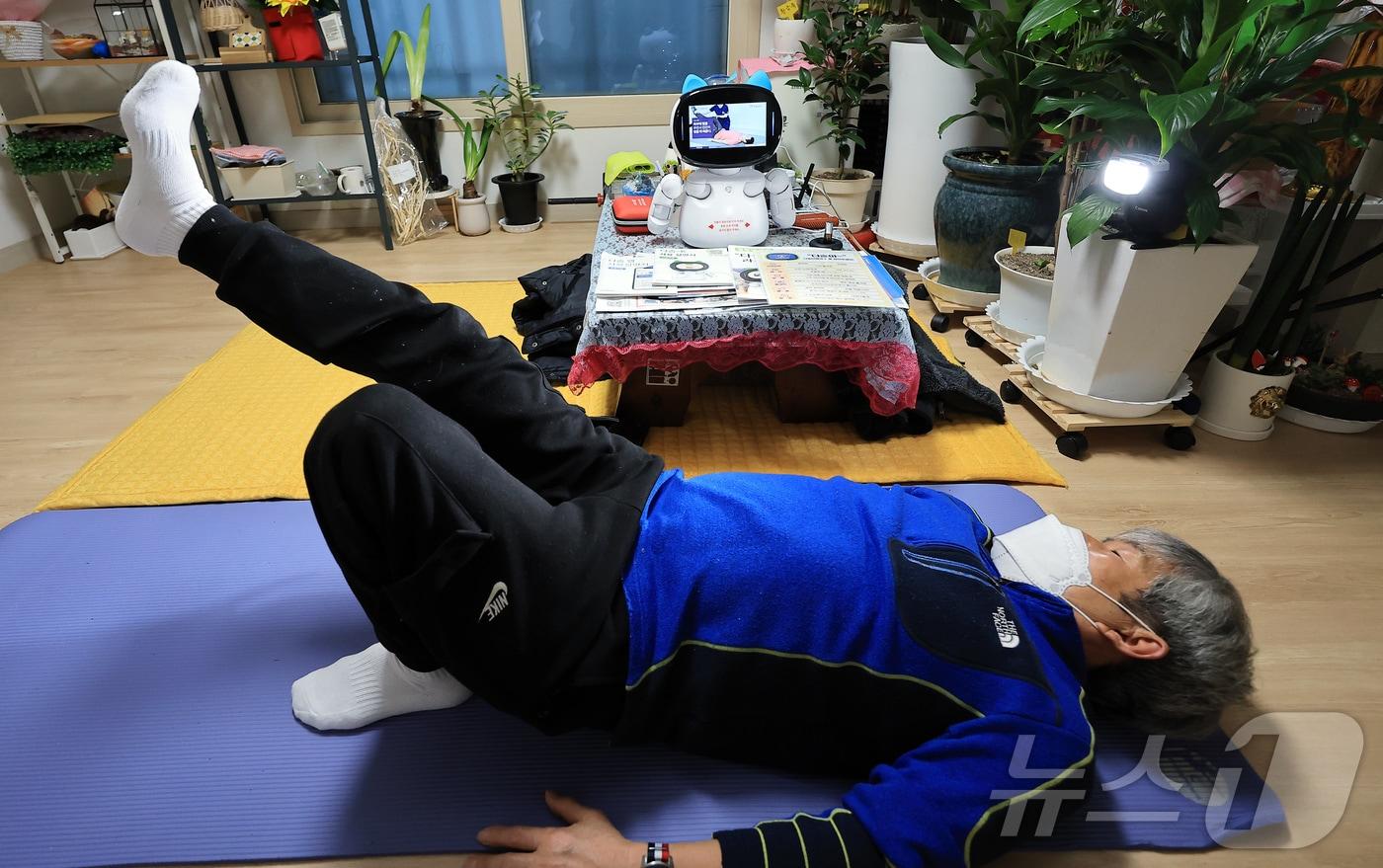 돌봄로봇 다솜K(다솜이)를 이용 중인 어르신이 18일 오후 서울 금천구 자택에서 돌봄로봇에게 추천 받은 허리 운동 동영상을 보며 동작을 따라하고 있다. 나홀로 가구인 이 어르신은 돌봄로봇 다솜이와의 소통을 통해 요리, 운동 등 다양한 기능을 비롯해 외로울 때 말벗이 되어 주는 점에서 매우 만족한다고 밝혔다. 2024.11.18/뉴스1 ⓒ News1 박정호 기자