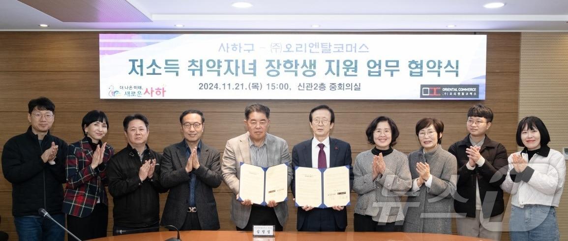 본문 이미지 - 부산 사하구와 오리엔탈코머스 관계자들이 저소득 취약자녀 장학생 업무 협약을 맺고 기념사진을 찍고 있다.(사하구 제공)