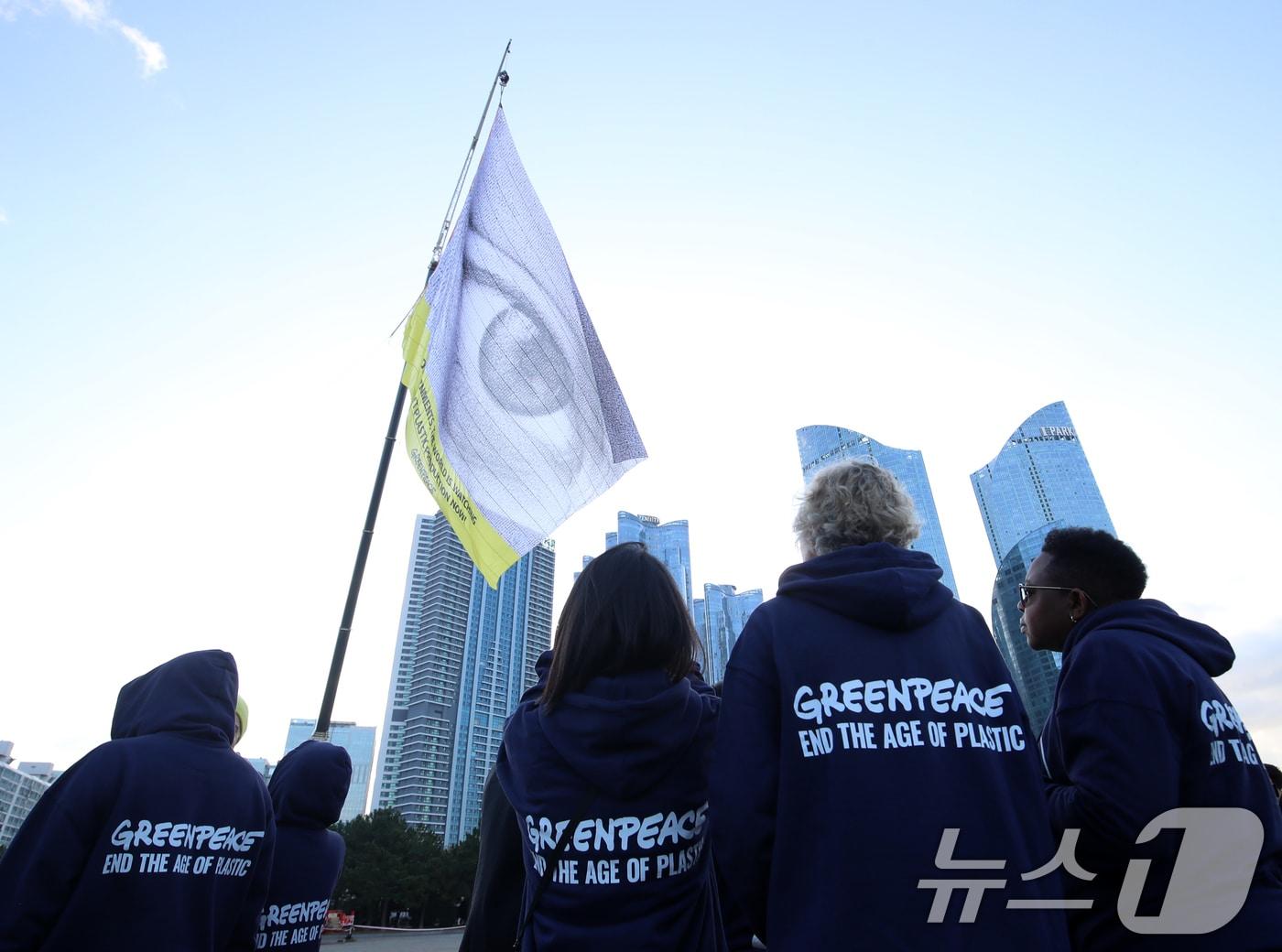본문 이미지 - 25일 오전 국제 플라스틱 협약 제5차 협상회의(INC5)를 앞두고 국제 환경보호 단체인 그린피스가 부산 해운대구 수영만요트경기장 내 건물 10층 높이의 크레인에 가로 30m, 세로 24m 크기의 초대형 눈 형상 깃발을 설치해 퍼포먼스를 벌이고 있다.  2024.11.25/뉴스1 ⓒ News1 윤일지 기자