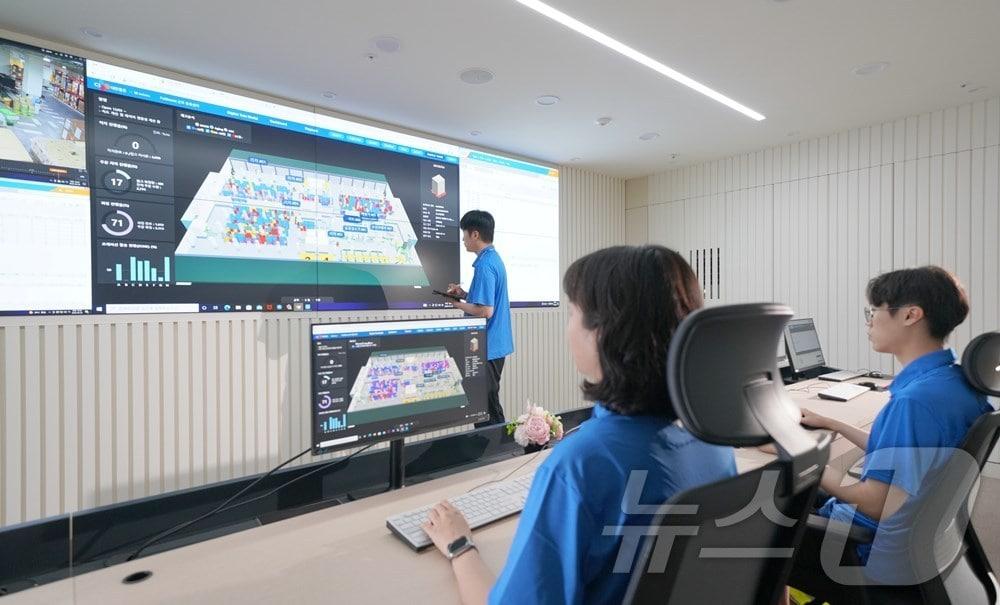 본문 이미지 - 군포풀필먼트센터 관제실에서 CJ대한통운 직원들이 디지털트윈 기술을 활용해 입출고 과정 및 재고상태 등 물류 전과정을 살펴보고 있다.(CJ대한통운 제공)