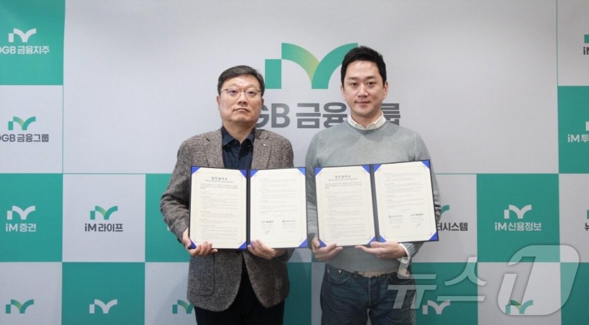 본문 이미지 - 진영수 iM뱅크 그룹장(왼쪽)과 이성봉 지엔터프라이 대표가 소상공인 금융 활성화를 업무협약을 체결한 뒤 협약서를 펼쳐 보이고 있다.(iM뱅크 제공)