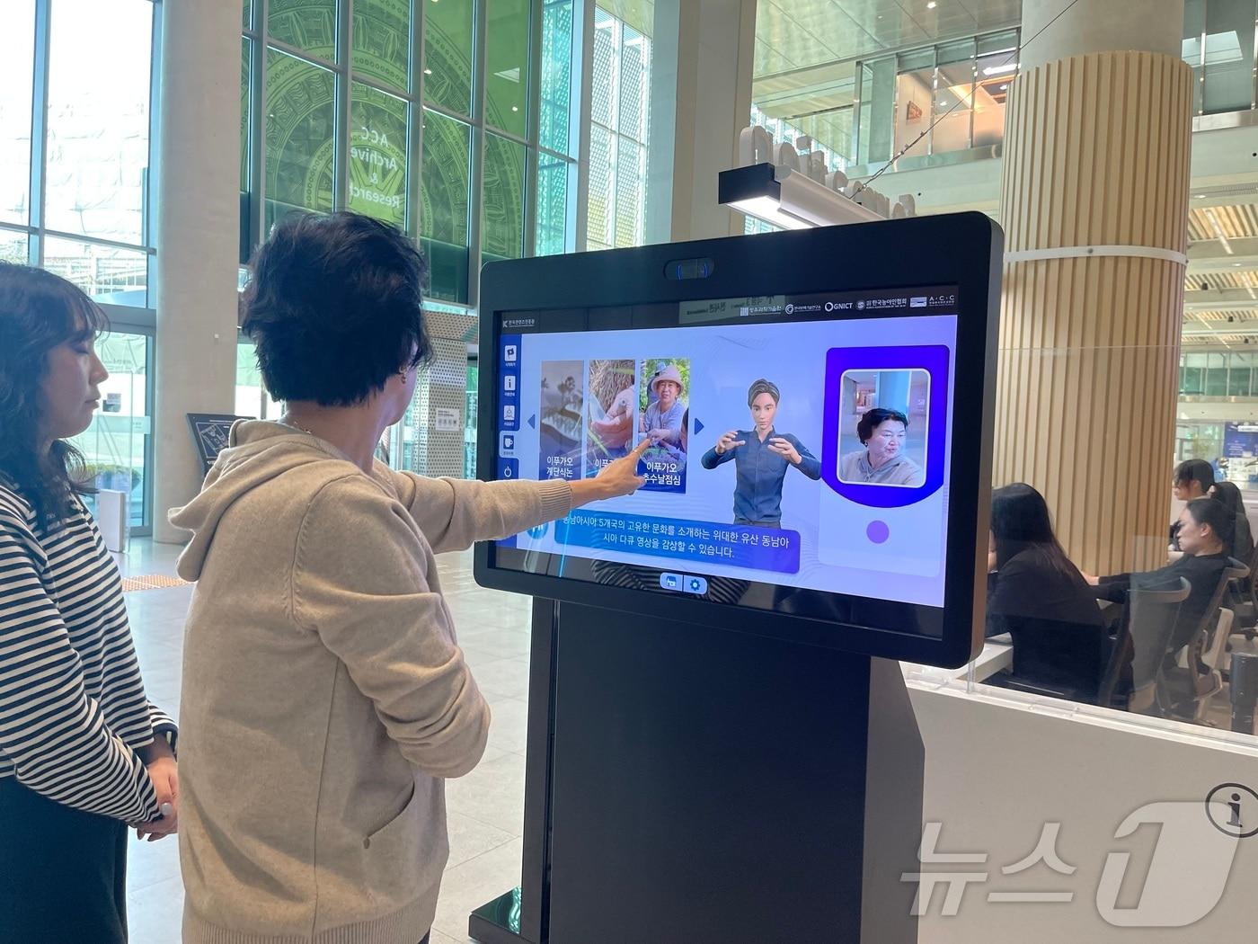 본문 이미지 - 국립아시아문화전당 문화정보원 안내데스크 옆에 설치된 청각장애인을 위한 수어 통·번역 체험용 키오스크를 방문객이 이용하고 있다. 2014.10.5(지스트 제공)/뉴스1 