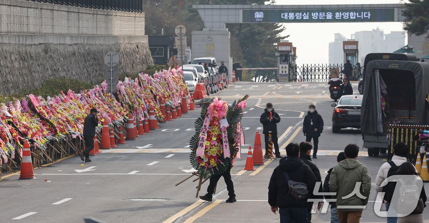 본문 이미지 - 11일 오후 서울 용산구 대통령실 출입문 앞 도로에서 화환 업체 관계자가 윤석열 대통령 지지자들이 보낸 화환을 옮기고 있다. 2024.12.11/뉴스1 ⓒ News1 장수영 기자