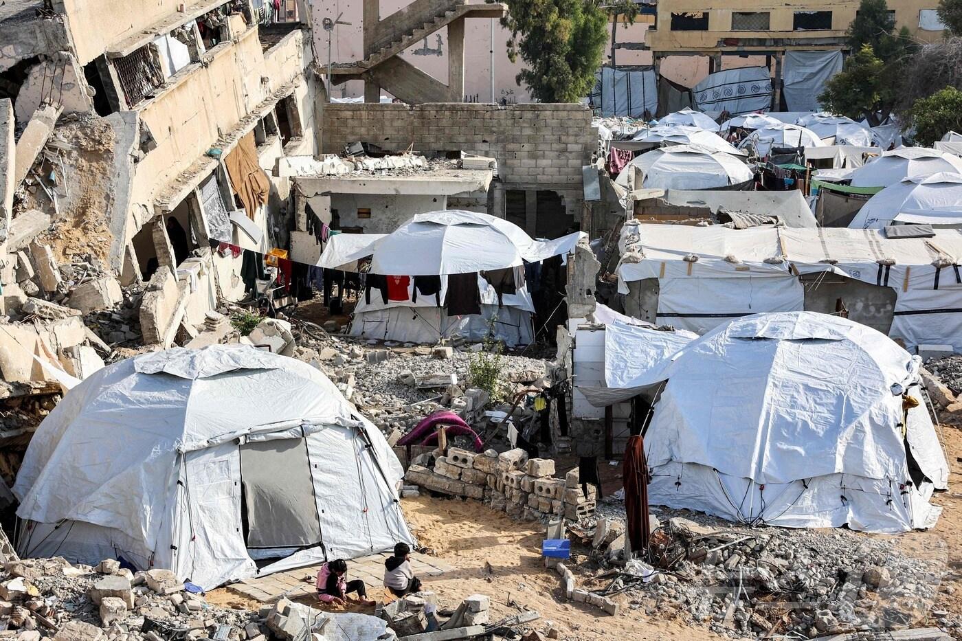 본문 이미지 - 11일 (현지시간) 가자 지구에서 하마스와 전쟁 중인 이스라엘 군의 포격을 받아 파괴된 건물 옆에 팔레스타인 피난민의 텐트가 설치돼 있다. 2024.12.12 ⓒ AFP=뉴스1 ⓒ News1 우동명 기자