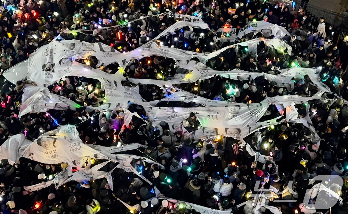12일 오후 서울 여의도 국민의힘 중앙당사 앞에서 열린 윤석열 대통령 탄핵 촉구 촛불 집회에 참여한 시민들이 윤석열 대통령에 대한 탄핵소추안 표결에 불참한 여당 의원들의 얼굴이 담긴 현수막을 찢고 있다. 2024.12.12/뉴스1 ⓒ News1 이강 기자