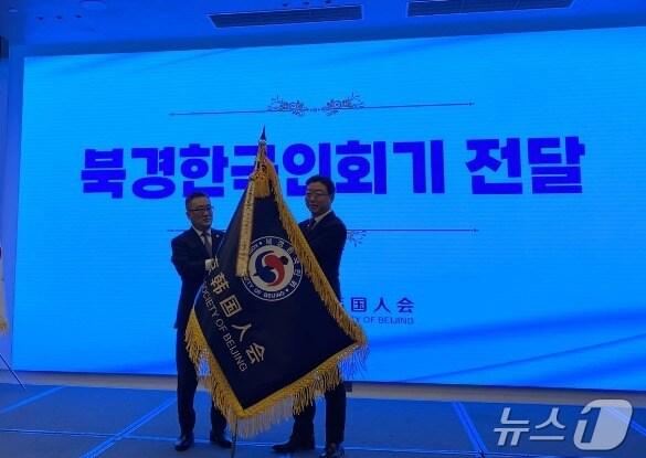 본문 이미지 - 서만교 신임 북경한국인회 회장(오른쪽)과 박기락 전 회장이 북경한국인회기를 들고 있다ㄱ