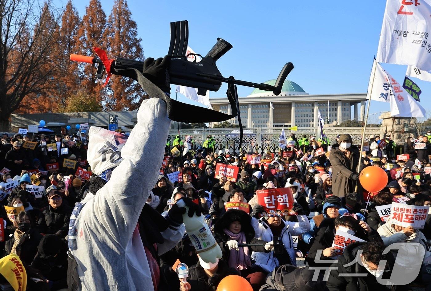 본문 이미지 - 윤석열 대통령에 대한 탄핵소추안 표결이 예정된 14일 오후 서울 여의도 국회의사당 앞에서 열린 윤석열 즉각 탄핵 범국민 촛불대행진에 참여한 한 시민이 국회 앞에서 장난감 총을 들어 비상계엄을 발동했던 대통령을 풍자하고 있다. 2024.12.14 ⓒ 뉴스1 박정호 기자