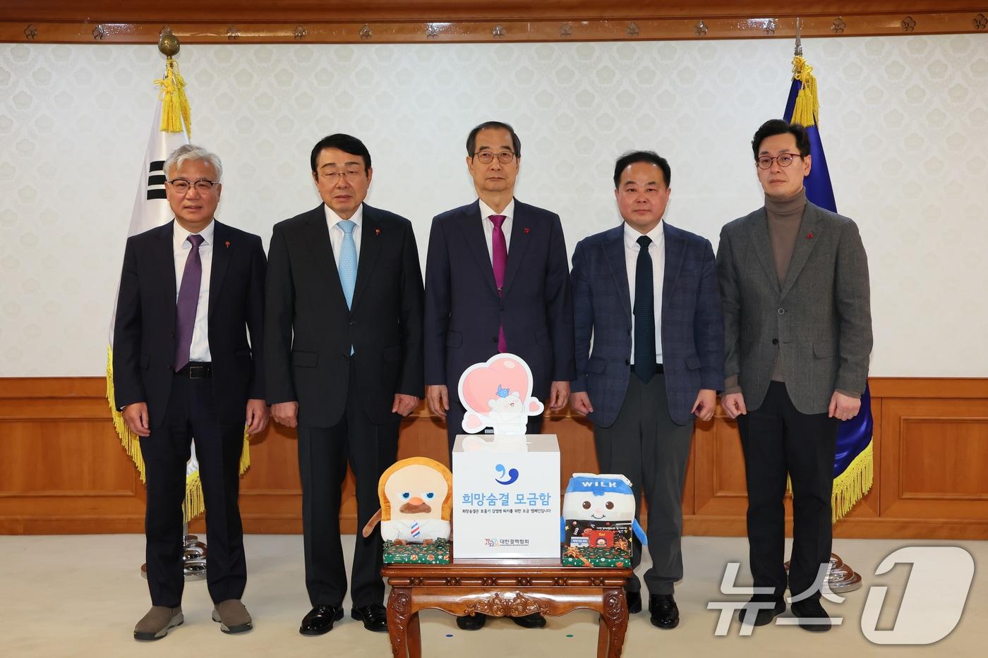 한덕수 대통령 권한대행 국무총리가 18일 오후 서울 종로구 정부서울청사에서 신민석 대한결핵협회 협회장으로부터 크리스마스 씰을 증정받고, 성금을 전달하고 있다. (총리실 제공) 2024.12.18/뉴스1