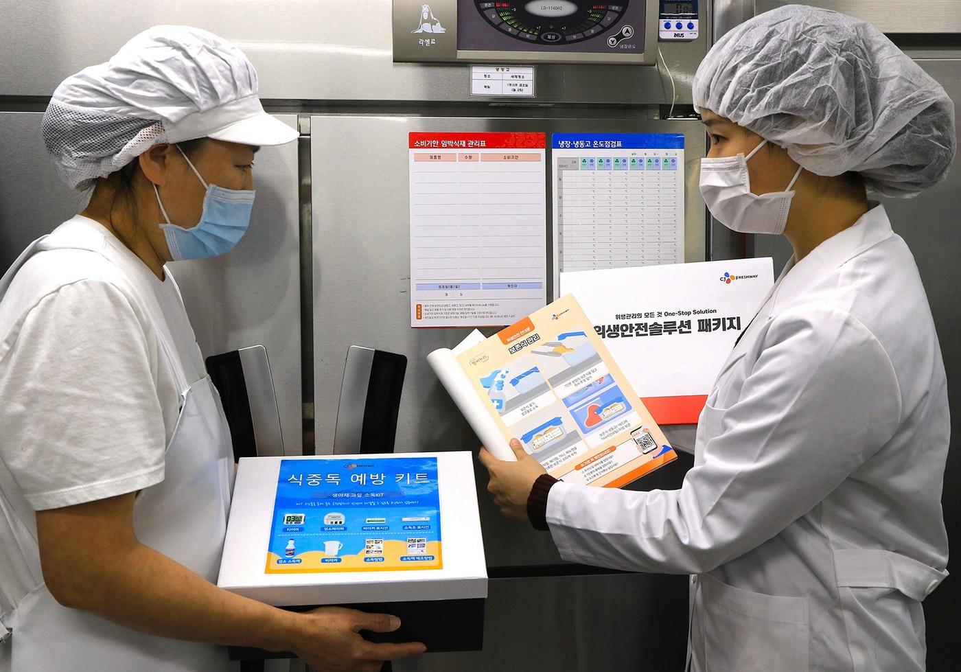 본문 이미지 - 지난 28일,서울시 마포구 아현실버복지관 급식 조리실에서 CJ프레시웨이 식품안전 담당자가 (왼쪽)조리사에게 위생안전 솔루션을 제공하고 있는 모습(CJ프레시웨이 제공).