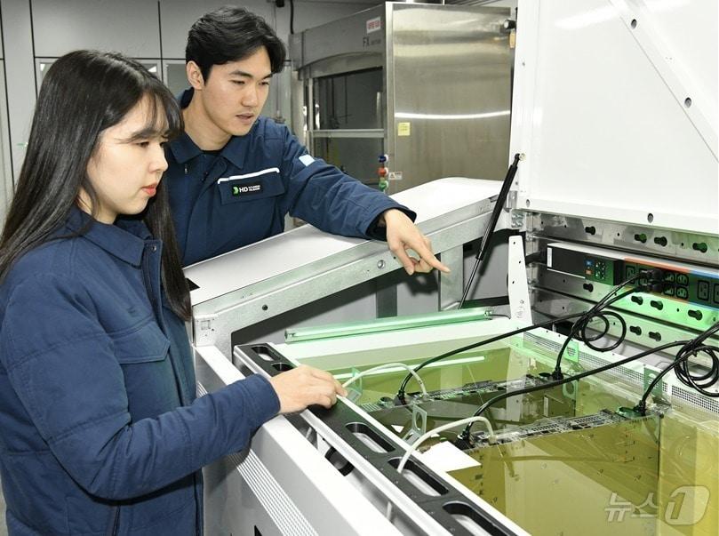 본문 이미지 - 액침냉각설비에 담긴 냉각유와 서버를 테스트하고 있는 HD현대오일뱅크 직원들.&#40;HD현대오일뱅크 제공&#41; ⓒ News1