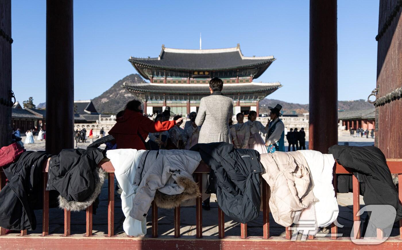 본문 이미지 - 아침 기온이 떨어지며 추운 날씨를 보인 22일 오후 서울 종로구 경복궁을 찾은 외국인 관람객들이 사진촬영을 위해 외투를 잠시 벗어놓고 있다. 2024.12.22/뉴스1 ⓒ News1 이승배 기자