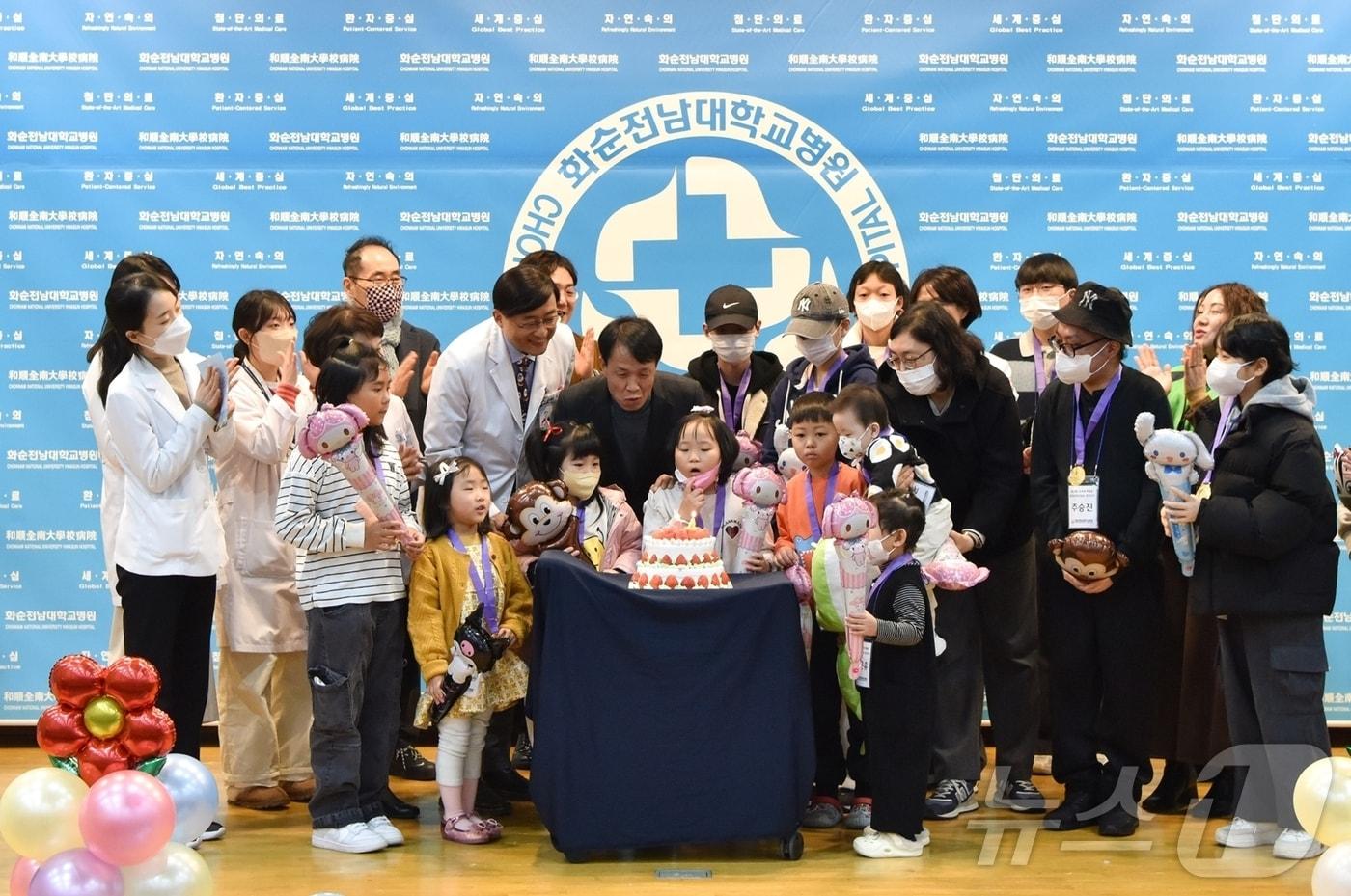 의료진과 교육청 관계자 등 참석자들이 힘든 투병 생활을 이겨낸 환아, 가족들과 함께 케이크 촛불을 끄고 있다.(화순전남대병원 제공) 2024.12.26