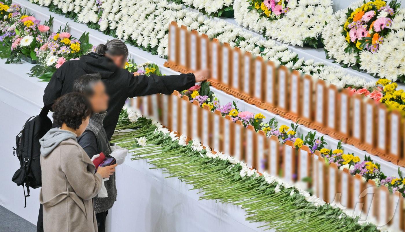 본문 이미지 - 30일 오후 전남 무안군 무안종합스포츠파크에 마련된 제주항공 여객기 사고 희생자 합동분향소에서 한 조문객이 희생자의 명패를 어루만지고 있다. (공동취재) /뉴스1 ⓒ News1 김민지 기자