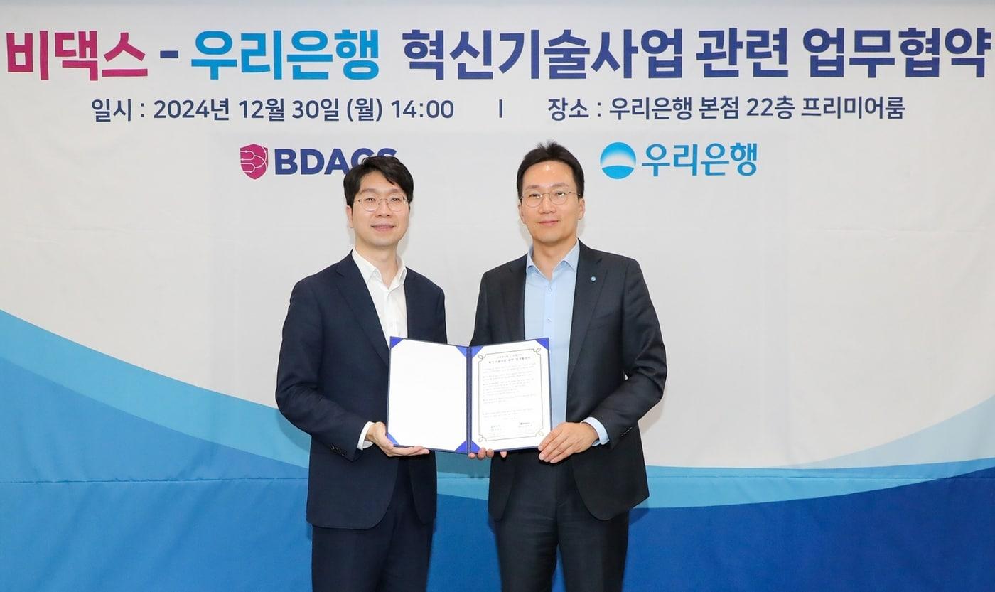 우리은행이 30일 은행 본점에서 비댁스와 혁신기술사업 관련 업무협약&#40;MOU&#41; 체결 후 &#40;왼쪽부터&#41; 류홍열 비댁스 대표, 옥일진 우리은행 디지털전략그룹장이 기념사진을 촬영하고 있다 &#40;우리은행 제공&#41;