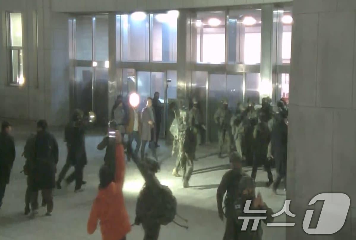 본문 이미지 - 국회사무처가 계엄군의 국회 본관 진입 과정이 담긴 CCTV를 4일 공개했다. 김민기 국회사무총장은 국방부가 헬기로 24차례에 걸쳐 무장한 계엄군 230여 명을 국회 경내로 진입시켰다며 0시 40분에는 계엄군 50여 명을 추가로 국회 외곽 담장을 넘어 진입시켰다고 전했다. 사진은 국회 본관 진입을 시도하는 계엄군 모습. (국회사무처 제공) 2024.12.4/뉴스1