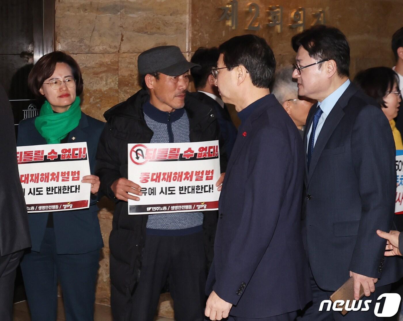 본문 이미지 - 정의당과 한국노총 및 민주노총 회원들이 '중대재해처벌법 개악 협상 중단 촉구' 피켓팅을 하는 가운데 홍익표 더불어민주당 원내대표가 1일 서울 여의도 국회에서 비공개로 열린 더불어민주당 의원총회 회의장에 들어가고 있다. 2024.2.1/뉴스1 ⓒ News1 송원영 기자