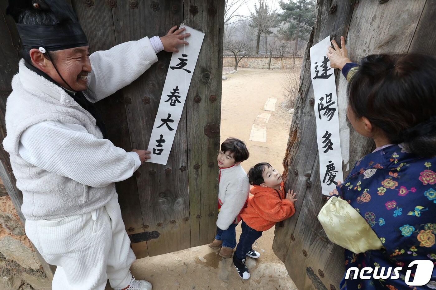 절기상 입춘(立春)을 사흘 앞둔 1일 경기 용인시 기흥구 한국민속촌에서 직원들이 새해의 복을 기원하는 마음을 담아 입춘첩을 대문에 붙이고 있다 입춘첩에는 보통 ‘입춘대길(立春大吉) 건양다경(建陽多慶)’(봄이 시작되니 크게 길하고, 경사스러운 일이 많이 생긴다.), ‘소지황금출(掃地黃金出) 개문만복래(開門萬福來)’(땅을 쓸면 황금이 생기고 문을 열면 만복이 온다) 등의 글씨를 써 붙였다. 봄을 기다리는 마음과 한 해 동안의 길한 운과 경사스러움이 가득하기를 기원하는 의미가 담겨있다. 2024.2.1/뉴스1 ⓒ News1 김영운 기자