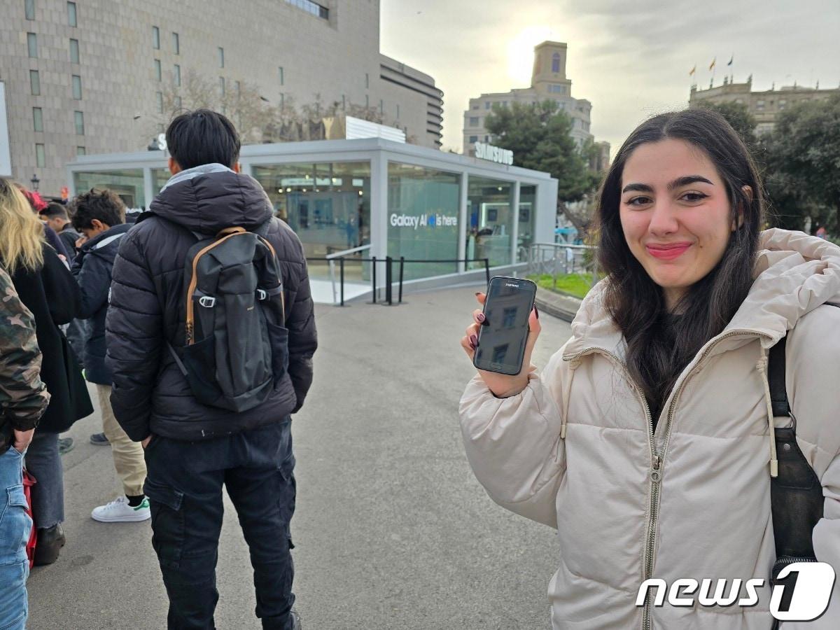 본문 이미지 - 25일(현지시각) 오전 스페인 바르셀로나 카탈루냐 광장에 마련된 '갤럭시 익스피리언스 스페이스' 앞에서 만난 사라(20·여)씨가 자신의 갤럭시 스마트폰을 들어보이며 웃고 있는 모습. /뉴스1 ⓒ News1  양새롬 기자