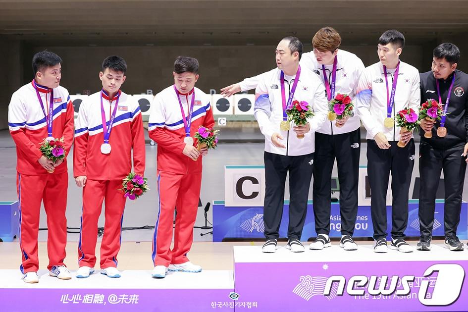 본문 이미지 - 25일 오후 중국 저장성 항저우 푸양 인후 스포츠센터에서 열린 2022 항저우 아시안게임 남자 10ｍ 러닝타깃 단체전 시상식에서 금메달을 목에 건 대한민국 선수들이 2위를 차지한 북한 선수들에게 1위 시상대에 함께 올라 기념촬영 할 것을 권하고 있다. 북한 선수들은 이날 우리 선수들의 제안을 우물쭈물 거리다 끝내 거부했다. 우리 선수들 오른편으로는 함께 1위 단상에 오른 인도네시아 선수(3위)가 이를 의아하게 여기며 북한 선수들을 바라보고 있다. 2023.9.25 뉴스1 민경석 기자