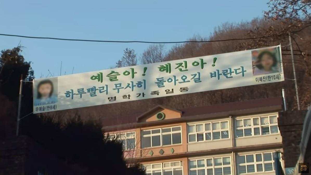 본문 이미지 - 2008년 1월 31일, 한 달 전 크리스마스에 실종된 두 아이를 애타게 찾는 현수막이 아이들의 학교 교문에 걸려있다. (KBS 갈무리)