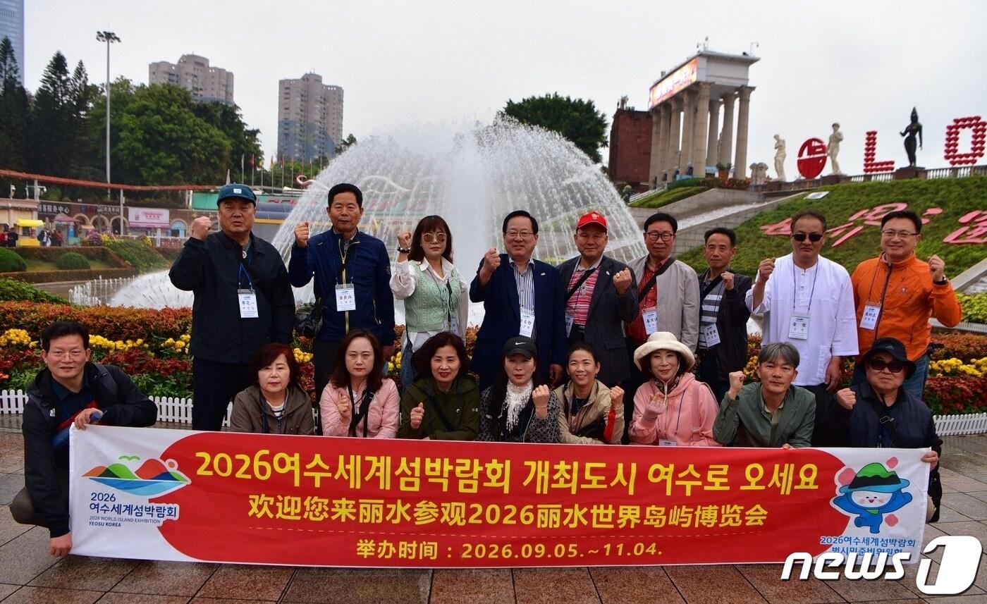 여수세계범시민준비위가 심천 '세계의 창' 분수 앞에서 '2026년 여수 방문을 환영한다'는 문구가 씌여진 현수막을 들고 사진을 찍고 있다.(여수세계범시민준비위 제공)2024.3.14/