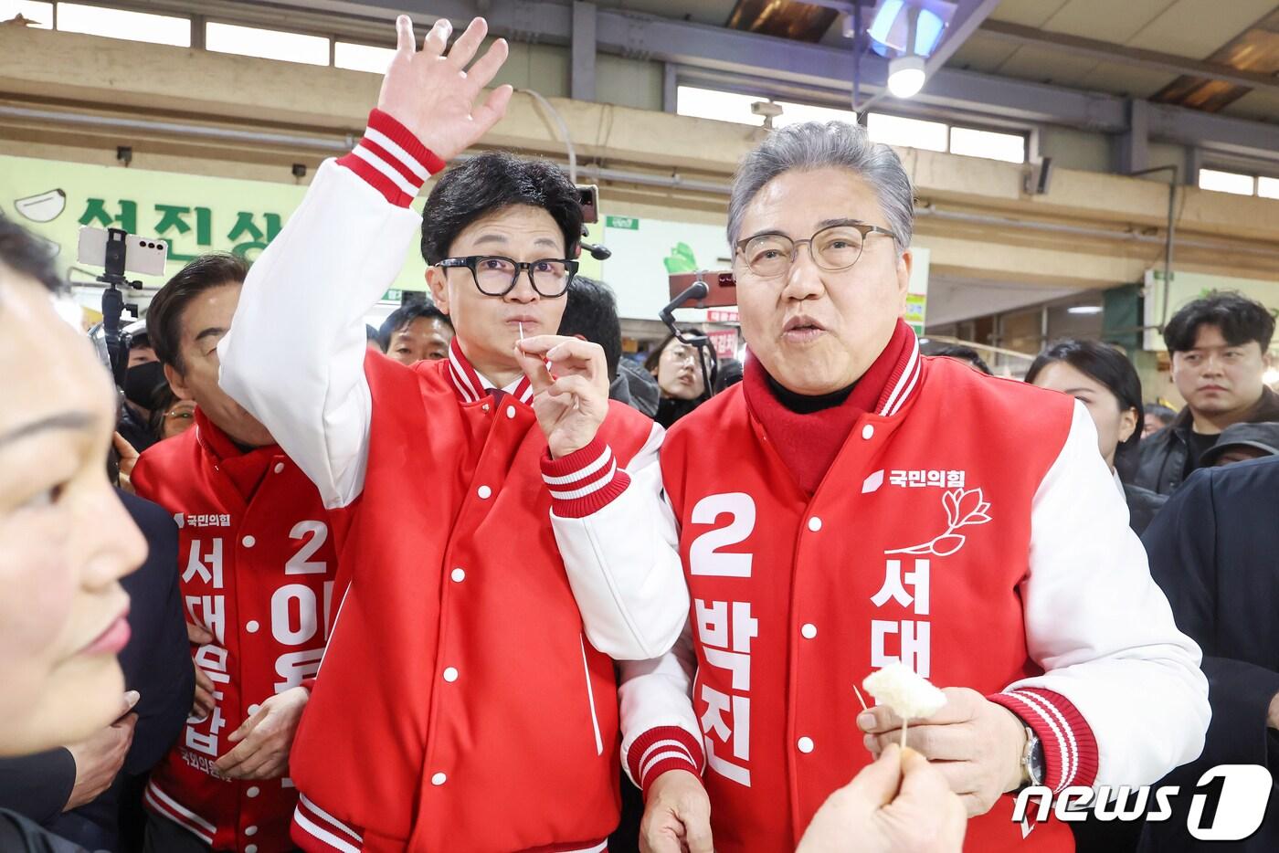 본문 이미지 - 한동훈 국민의힘 총괄선대위원장이 19일 오후 서울 서대문구 인왕시장에 이용호 서대문갑·박진 서대문을 후보와 함께 방문해 상인들에게 받은 떡을 맛보고 있다. 2024.3.19/뉴스1 ⓒ News1 민경석 기자