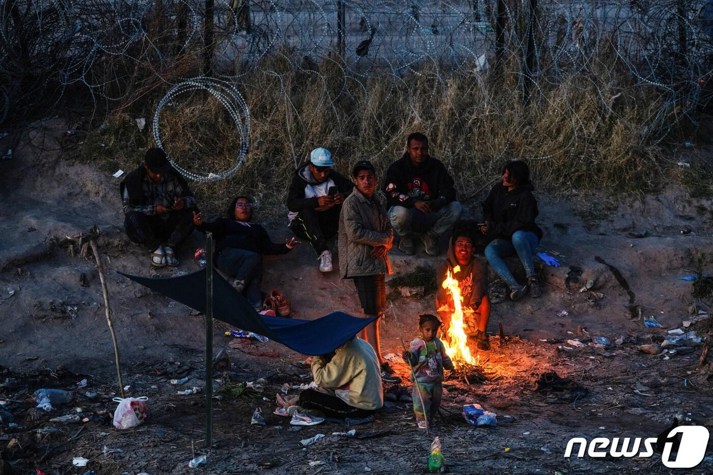 19일(현지시간) 미국-멕시코 국경을 흐르는 리오그란데강에서 미국에 입국을 시도하려는 이민자 가족이 모닥불을 피우고 있다. 미국 대법원은 이날 불법 입국자를 체포·구금할 수 있게 하는 텍사스주 이민법 'SB4'를 당분간 시행할 수 있도록 판결했다. 2024.03.19/ ⓒ 로이터=뉴스1 ⓒ News1 박재하 기자