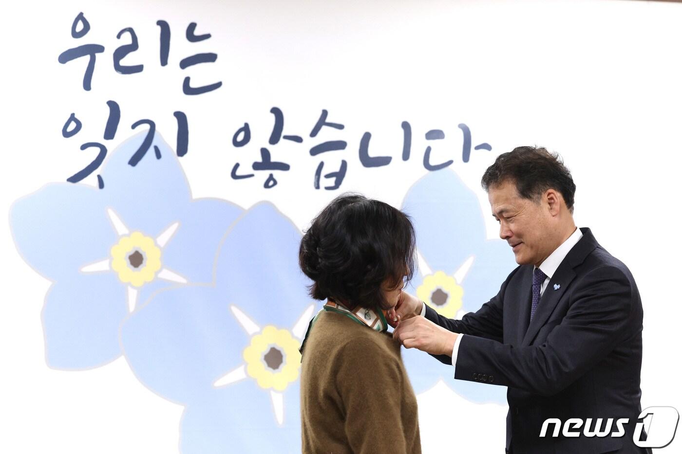 본문 이미지 - 김영호 통일부 장관이 지난 3월 서울 종로구 정부서울청사에서 열린 납북자·억류자·국군포로 가족 및 단체 간담회에서 참석자들에게 물망초 배지를 달아주고 있다. 물망초 배지는 북한에 억류돼 돌아오지 못하는 납북자·억류자·국군포로의 상징이다. 2024.3.27/뉴스1 ⓒ News1 신웅수 기자