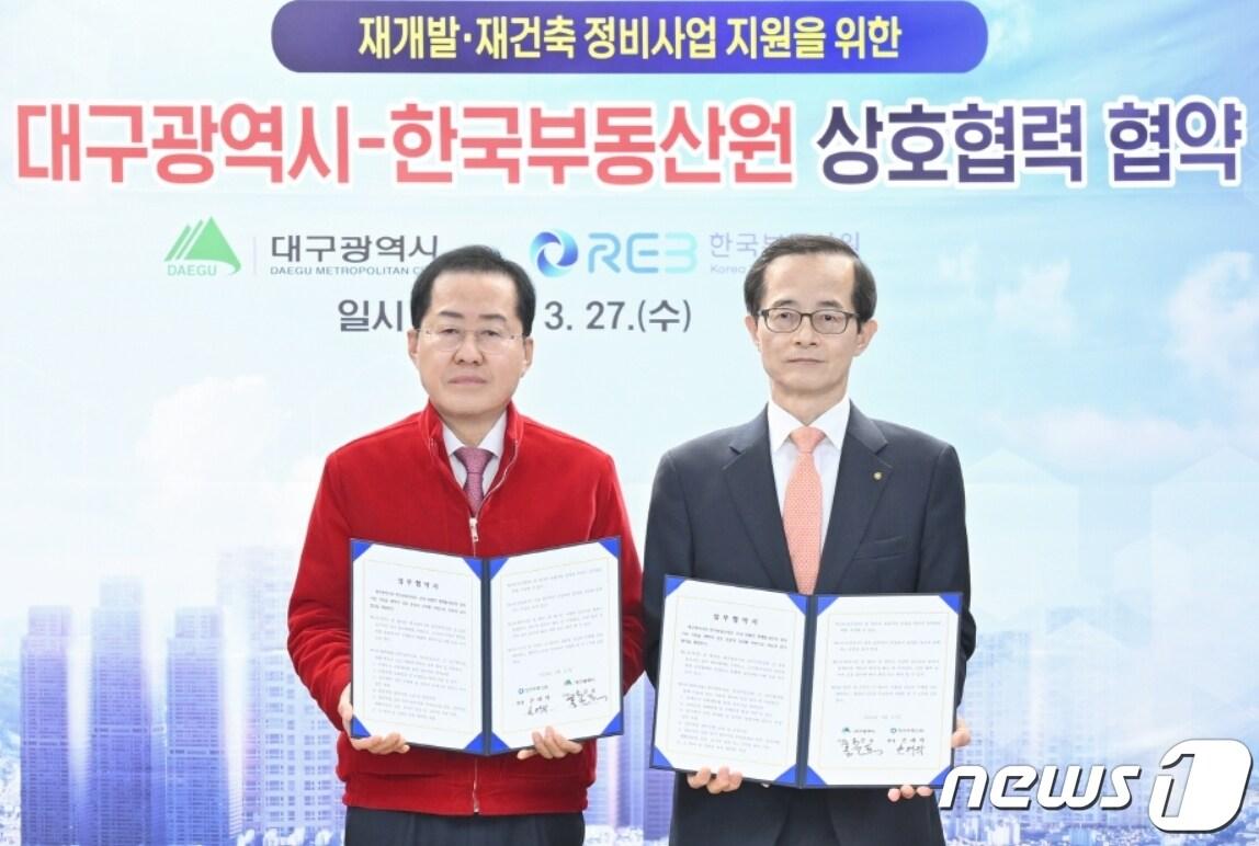 본문 이미지 - 27일 홍준표 대구시장(왼쪽)과 손태락 한국부동산원장이 재개발·재건축 정비사업 지원을 위한 업무협약을 체결한 뒤 협약서를 펼쳐 보이고 있다.(한국부동산원 제공)