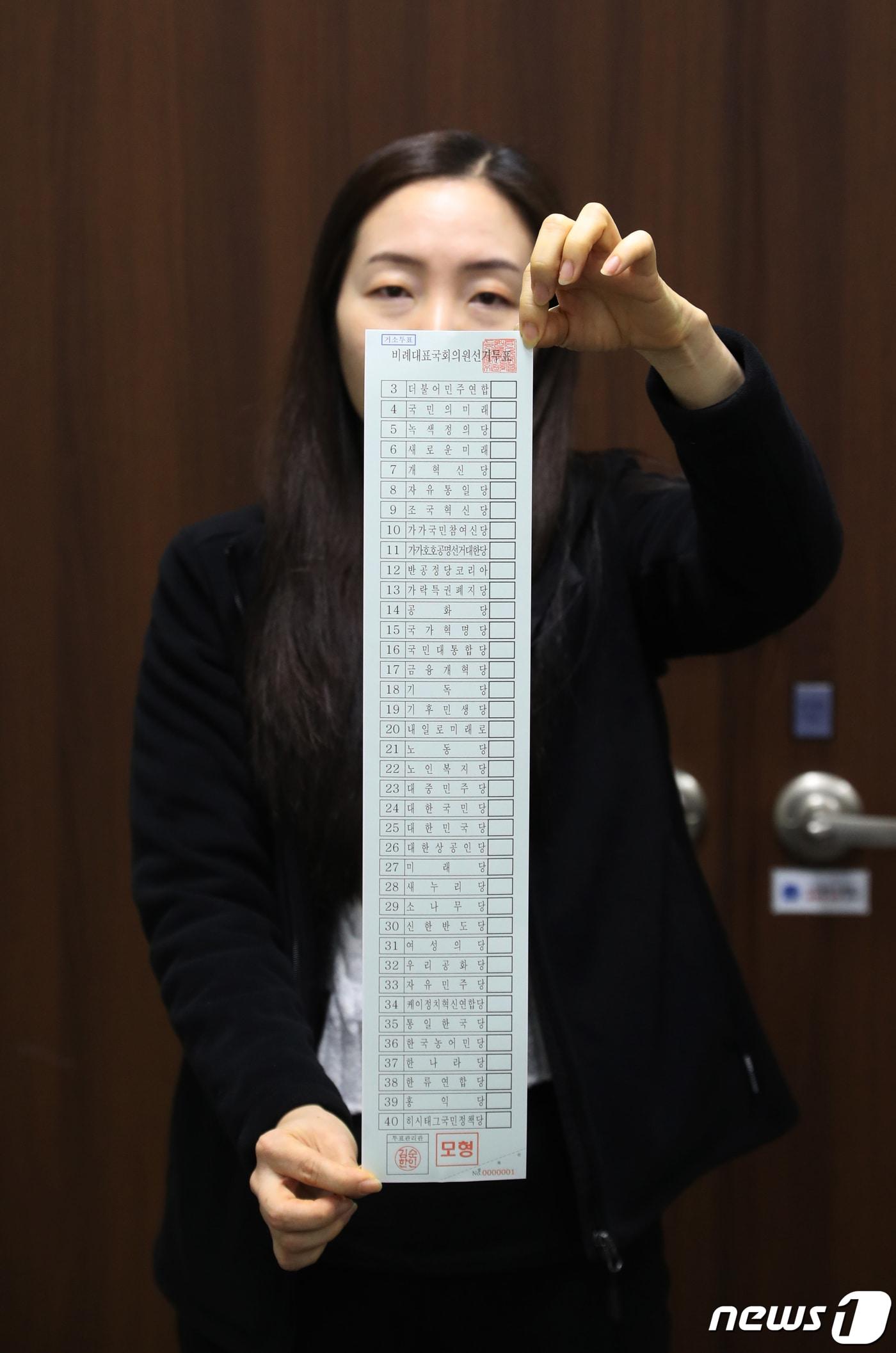 본문 이미지 - 제22회 국회의원 선거를 보름여 앞둔 28일 오후 경기 수원시 영통구선거관리위원회에서 선관위 관계자가 거소투표용 비례대표 국회의원 선거 투표용지 모형을 들어 보이고 있다. 이번 총선에서는 비례대표 후보 등록을 신청한 정당 38곳 모두 선거 참여가 확정되면서 비례대표 투표용지는 51.7cm로 역대 최장 기록을 세웠다. 2024.3.28/뉴스1 ⓒ News1 김영운 기자