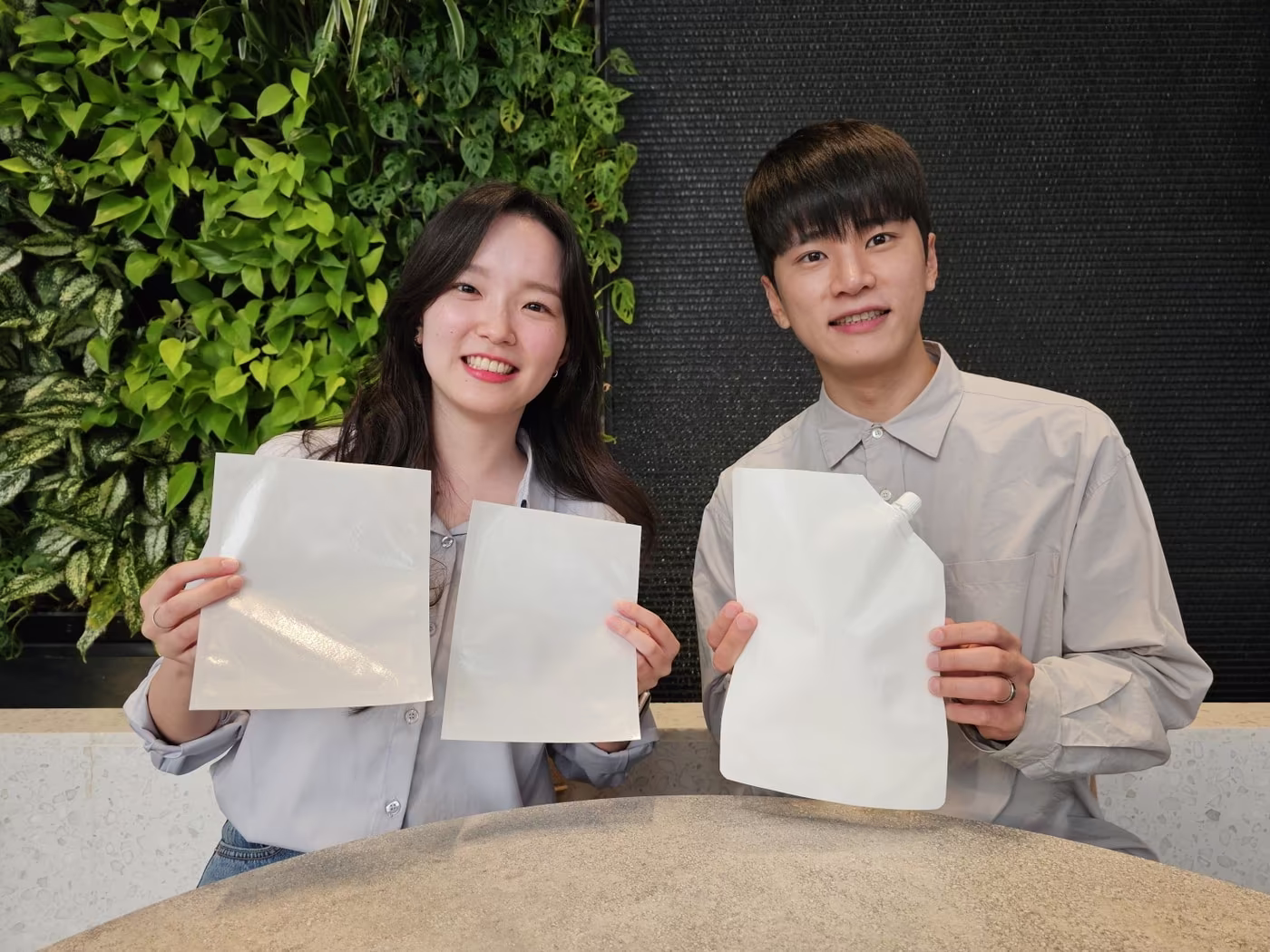 본문 이미지 - SK지오센트릭 구성원들이 SK지오센트릭의 단일 플라스틱 소재로 율촌화학이 제조한 포장재 시제품을 소개하고 있다.(SK지오센트릭 제공) 